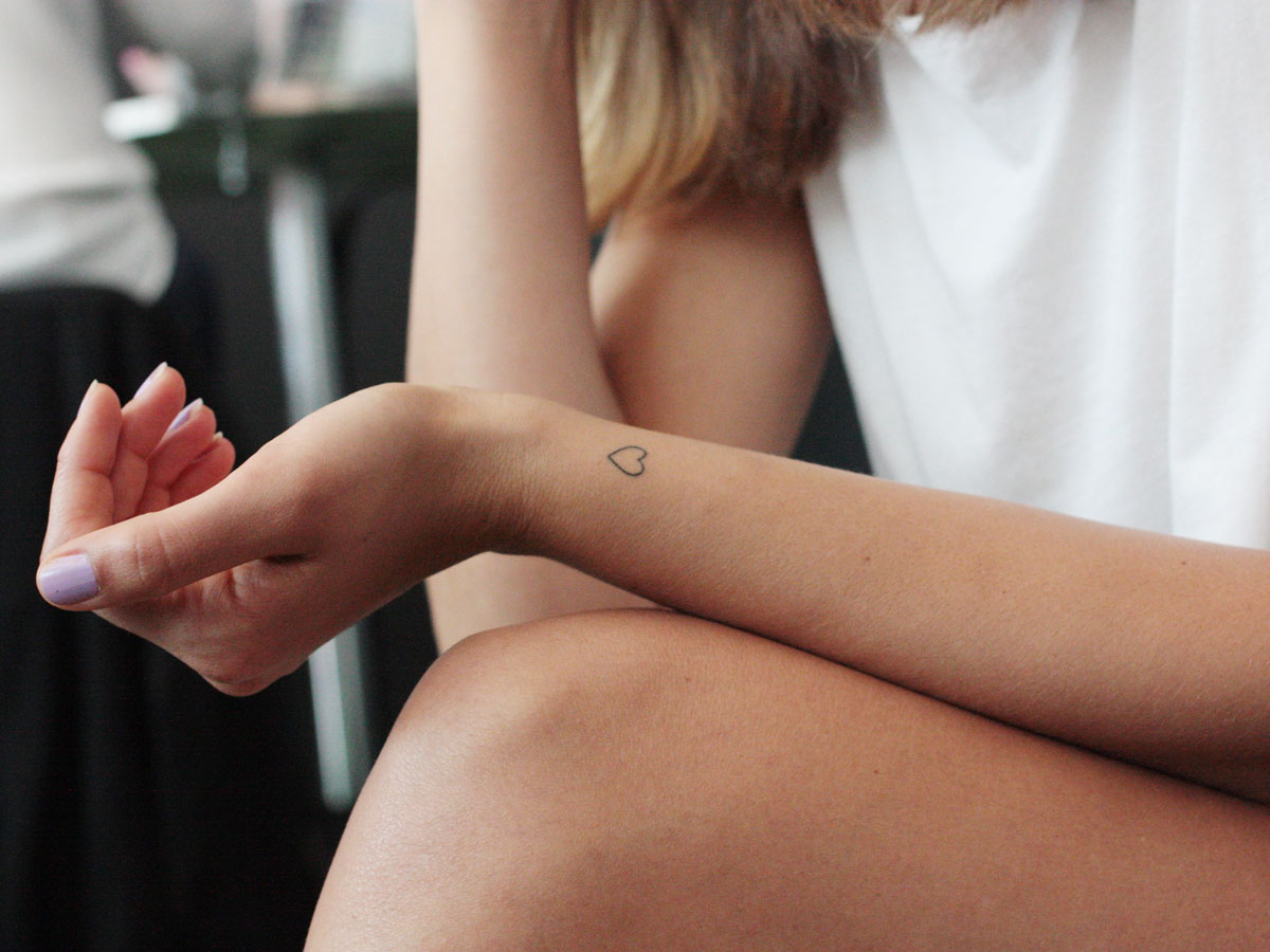Ausschnitt Frau von Arm mit Herz Tattoo und Bein sinnbildlich für Pflege Deumavan® Schutzsalbe
